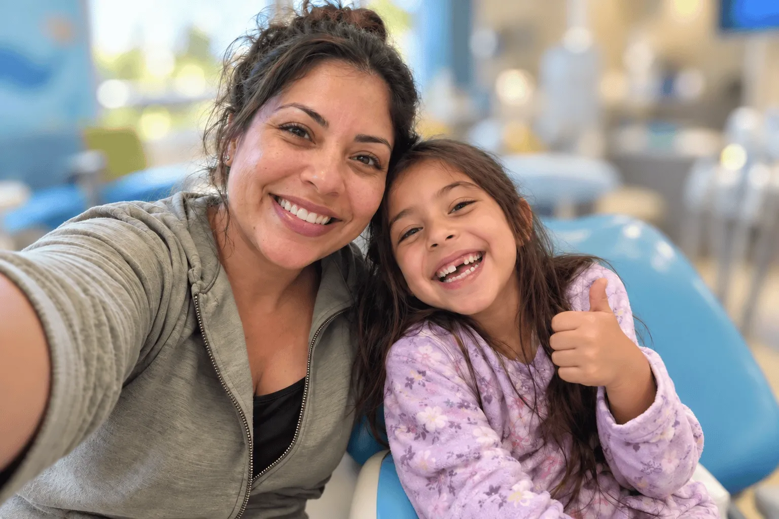Madre e hija sonriendo en el consultorio de odontopediatría
